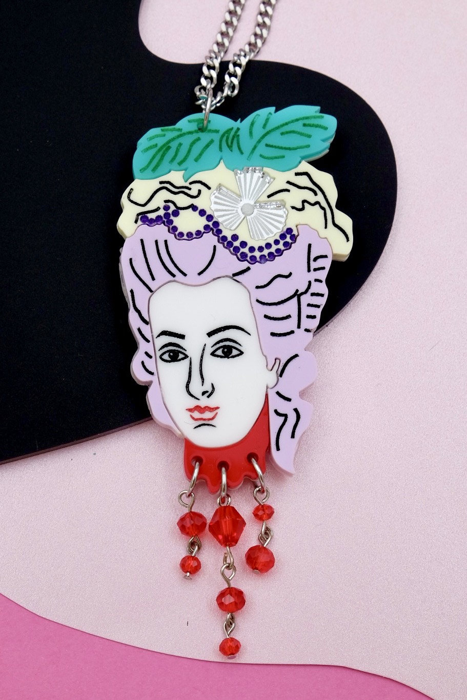 pendant necklace of Marie Antoinette's detached head with small red beads falling from the bottom